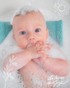 bébé allongé dans son bain avec de la mousse et du savon