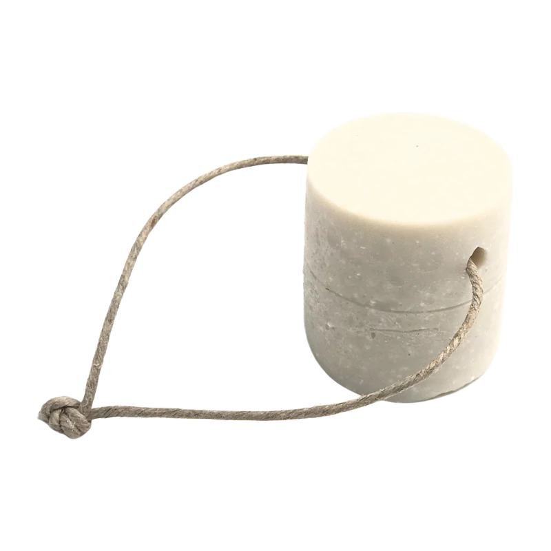 Un détachant solide pour le linge sous forme de cylindre blanc, accompagné d'une corde en fibre naturelle qui semble servir de manche ou de support pour le produit.