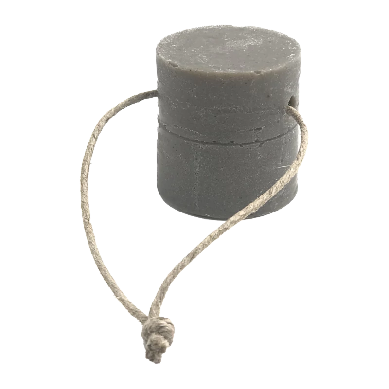 Détergent solide gris pour la vaisselle et le ménage, de forme cylindrique, avec une corde en jute naturelle qui semble servir de support.