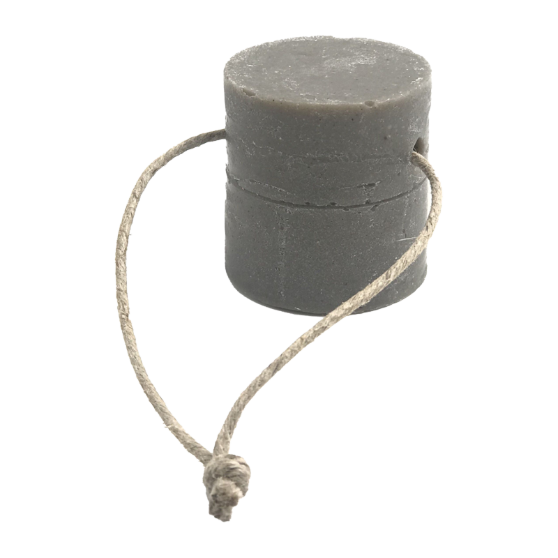 Détergent solide gris pour la vaisselle et le ménage, de forme cylindrique, avec une corde en jute naturelle qui semble servir de support.