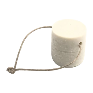 Un détachant solide pour le linge sous forme de cylindre blanc, accompagné d'une corde en fibre naturelle qui semble servir de manche ou de support pour le produit.