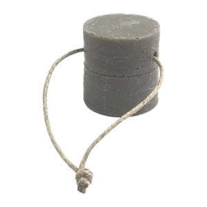 Détergent solide gris pour la vaisselle et le ménage, de forme cylindrique, avec une corde en jute naturelle qui semble servir de support.